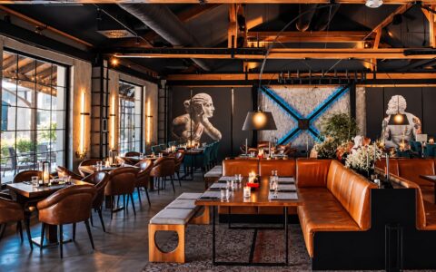 Enterijer restorana Insolita na Dorćolu sa kožnim separeima, drvenim gredama, statuama sa tetovažama i plavo osvetljenim zidom, spreman za veći događaj