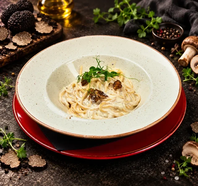 Pasta spageti tartufo restorana Insolita u kremastom sosu sa tartufima, servirana u dubokom tanjiru sa svežim mikrozelenjem.