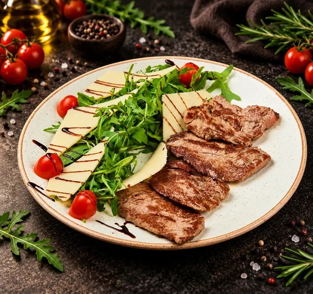 Taljata biftek restorana Insolita sa grilovanim mesom, rukolom, listićima tvrdog sira, čeri paradajzom i balsamiko prelivom.